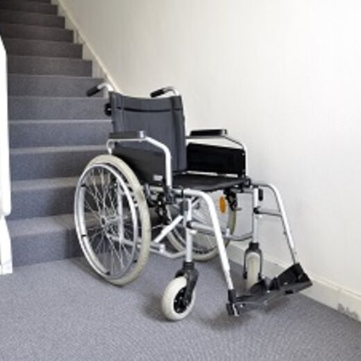 Ein leerer Rollstuhl am Ende einer Treppe im Haus
