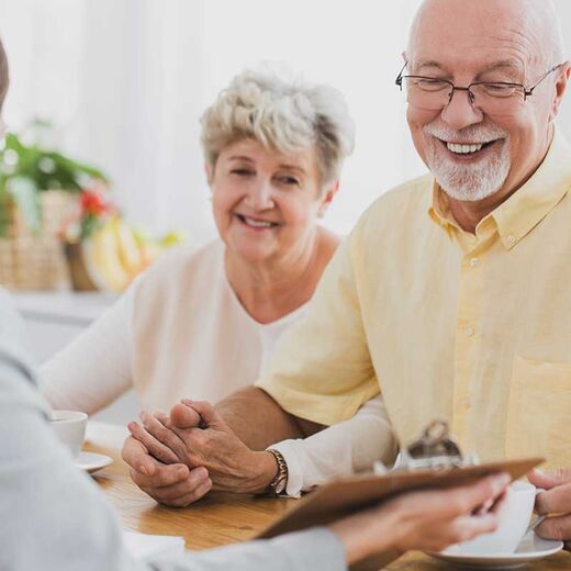 Seniorenpaar schauen lächelnd auf Versicherungsdokument