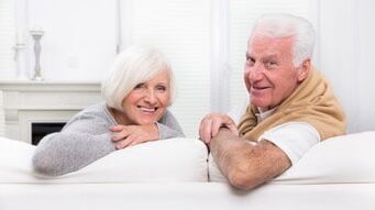 Ältere Mann und Frau sitzen auf einer Couch und schauen nach hinten