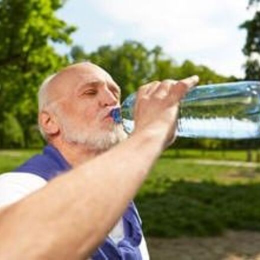 Senior im Park trinkt Wasser