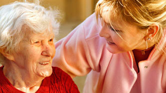 Eine Seniorin lächelt ihre Pflegerin an
