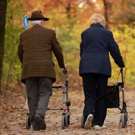 Mann und Frau gehen mit Rollator durch den Herbstwald