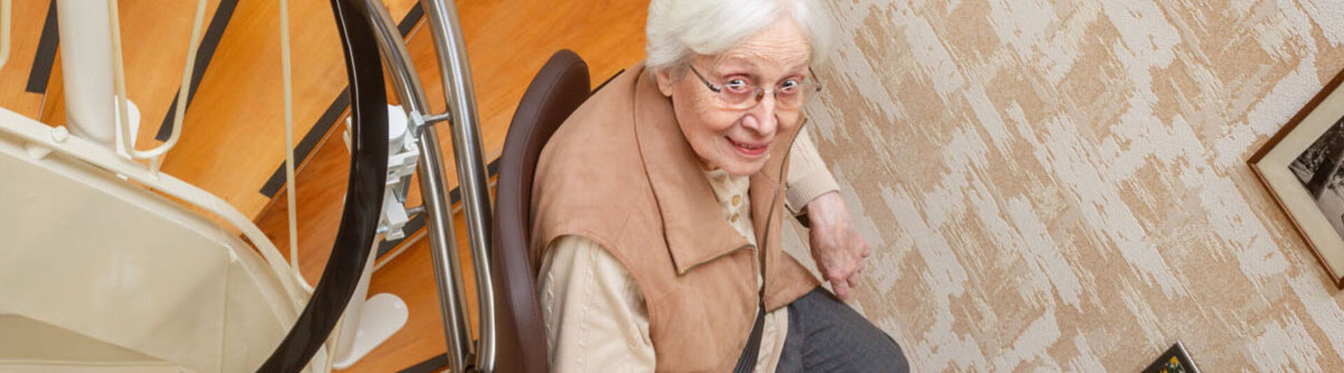 Seniorin fährt mit dem Treppenlift eine Wendeltreppe hoch