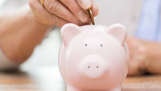 Gespartes Geld Münze wird in Sparschwein gesteckt