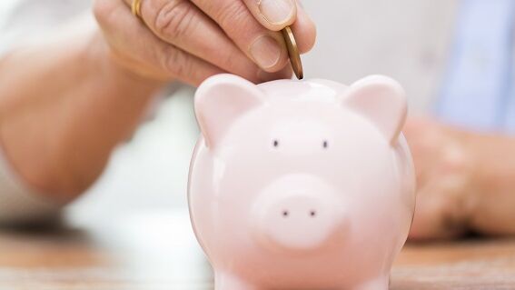 Münze wird in Sparschwein gesteckt