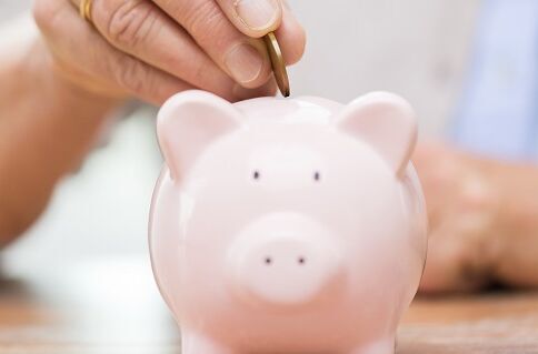 Gespartes Geld Münze wird in Sparschwein gesteckt