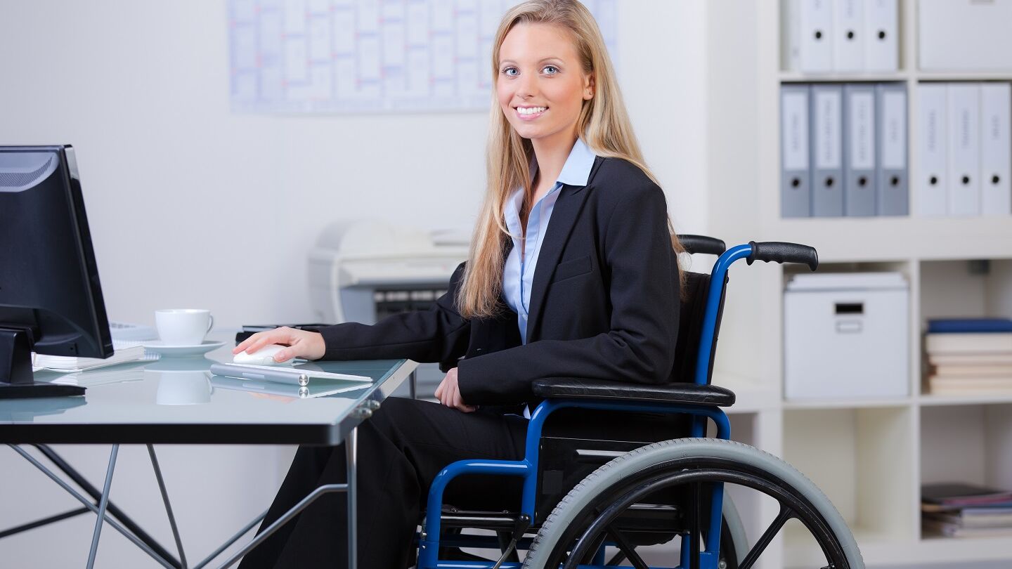 Rechte bei Behinderung: zufriedene Mitarbeiterin im Rollstuhl
