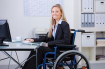 Rechte bei Behinderung: zufriedene Mitarbeiterin im Rollstuhl