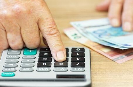 Senior tippt in den Taschenrechner und zählt Geld