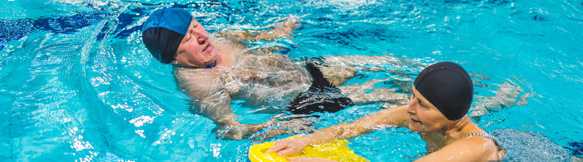 Seniorin und Senior beim Schwimmen im Hallenbad. © PoppyPix - stock.adobe.com