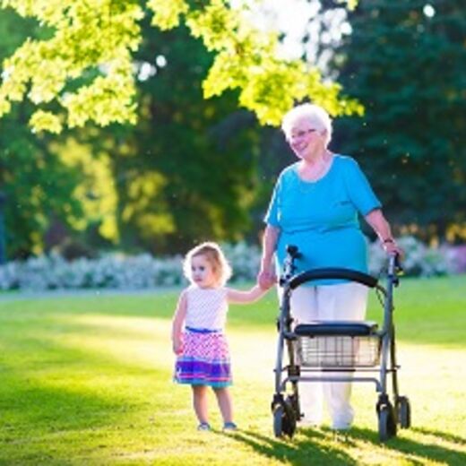 Senioren mit Rollator hält Kleinkind an der Hand im Park