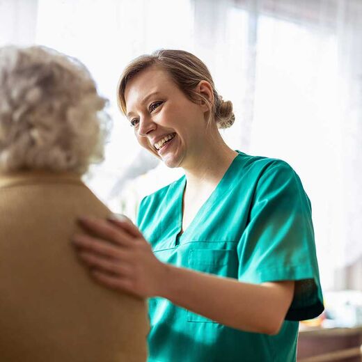Pflegerin hilft einer Seniorin 