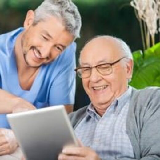Zwei Männer schauen lächelnd auf ein Tablet