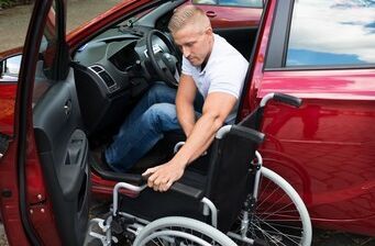 Behindertengerechtes Auto für Rollstuhlfahrer Ein Rollstuhlfahrer steigt in sein behindertengerechtes Auto ein