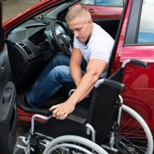 Ein Rollstuhlfahrer steigt in sein behindertengerechtes Auto ein