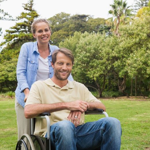Andreas Lanzen sitzt im Rollstuhl und seine Frau schiebt ihn