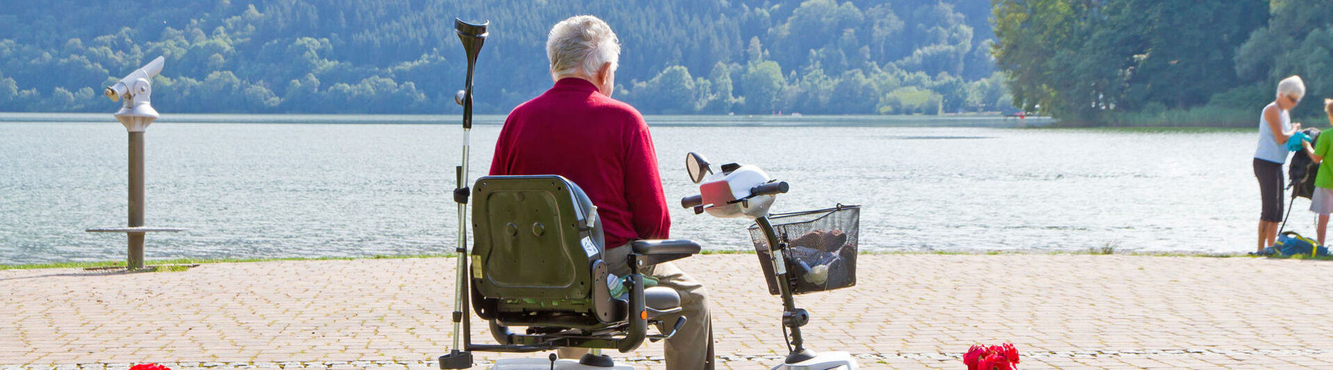 Renter in Rollstuhl schaut im Urlaub auf einen See