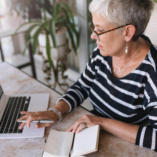 Seniorin am Laptop macht sich Notizen zum Testament.