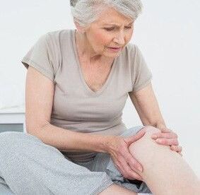 Frau hat Schmerzen im Knie beim Treppensteigen