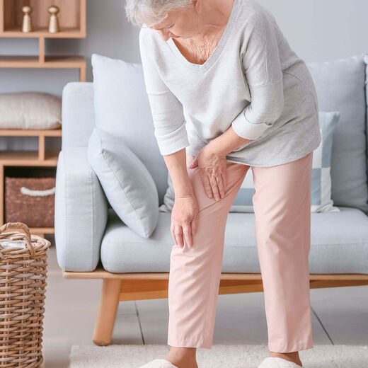 Seniorin fasst sich vor Schmerzen an ihr Knie