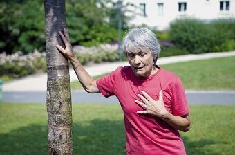 Eine Seniorin mit Atemnot hält sich den Brustkorb