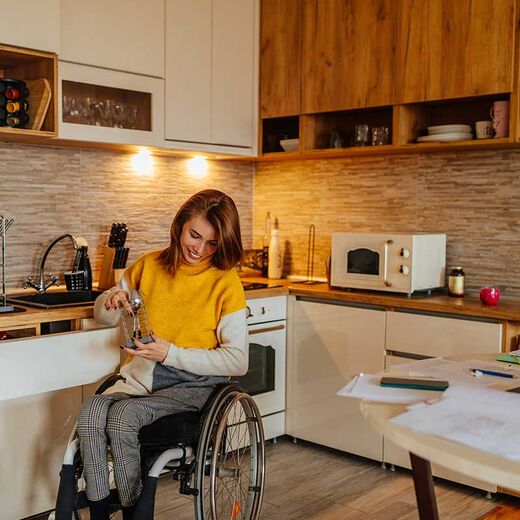 Zuschüsse für Menschen mit Behinderung: Ein Mann mit Beinprothesen in der Küche