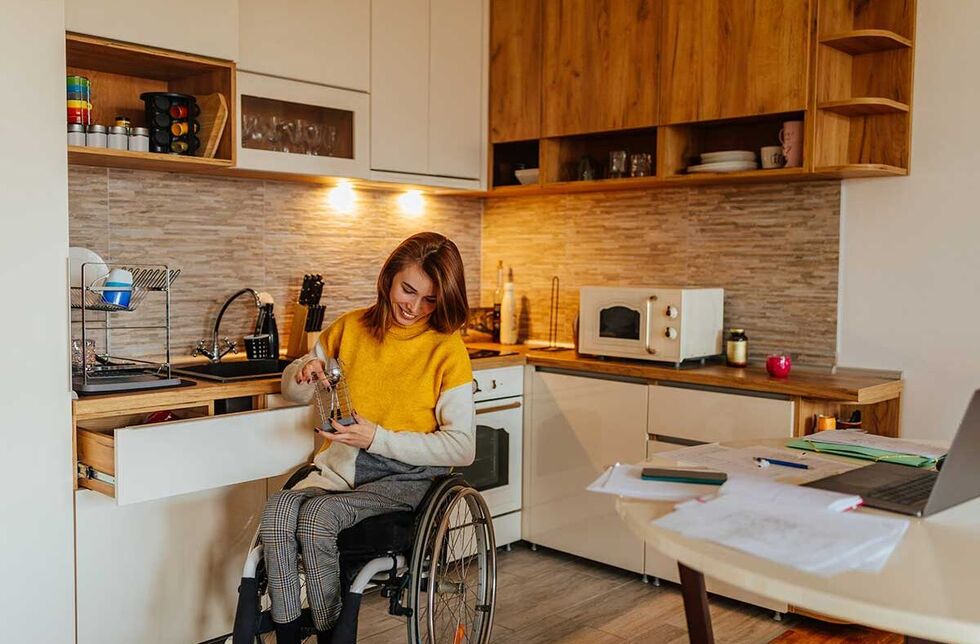 Zuschüsse für Menschen mit Behinderung: Ein Mann mit Beinprothesen in der Küche