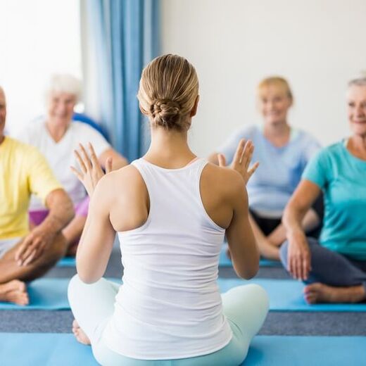 Senioren beim Yoga mit Yogalehrerin