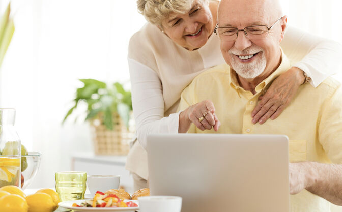 Eine Frau umarmt ihren Mann am Laptop