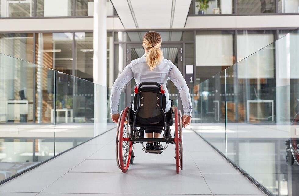 Frau fährt mit Rollstuhl durch den Büroflur