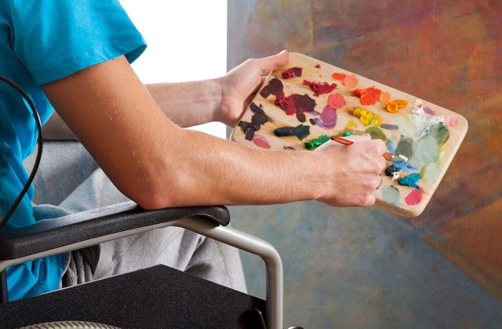Freizeitangebote für Menschen mit Behinderung: Person im Rollstuhl mit Farbpalette