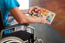 Freizeitangebote für Menschen mit Behinderung: Person im Rollstuhl mit Farbpalette