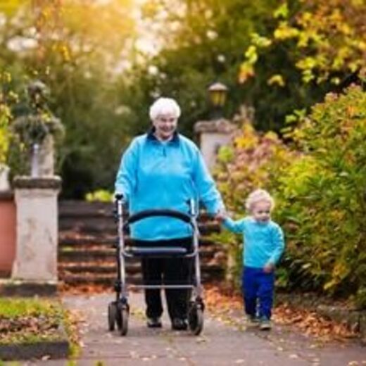 Seniorin geht mit Rollator und einem Kind an der Hand spazieren