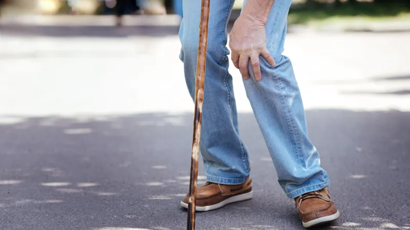 Älterer Herr greift sich ans Knie wegen Schmerzen