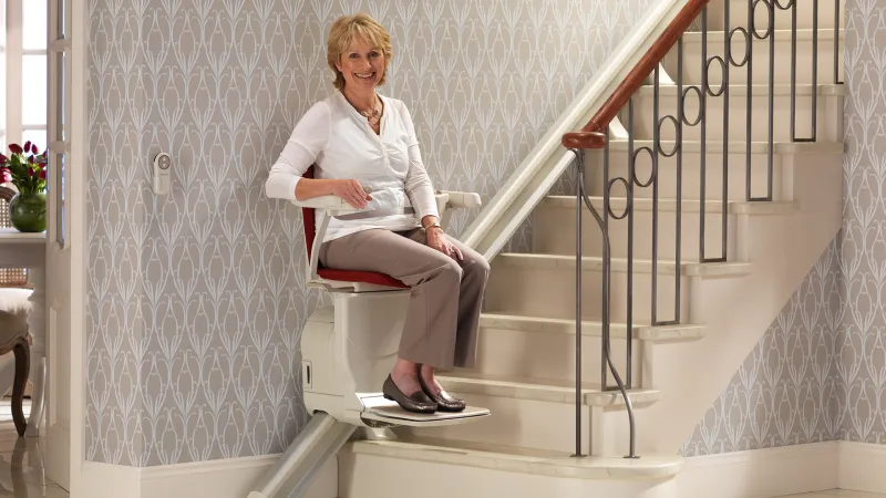 Frau im Sitzlift an der Treppe
